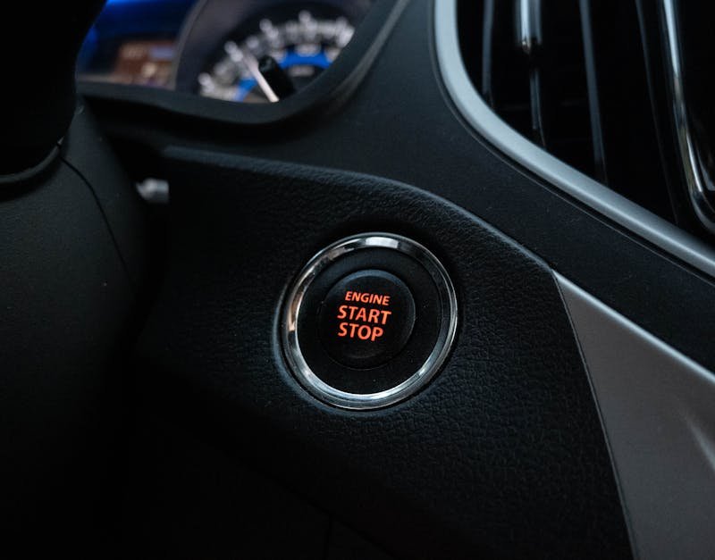 Close-up image of a car's engine start stop button on the dashboard.