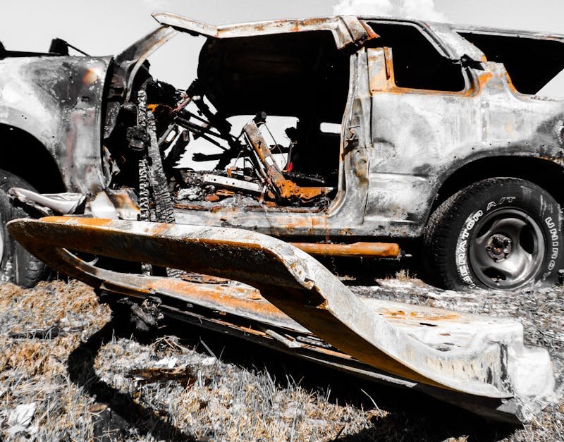 Close-up of a rusty, burnt-out vehicle wreck abandoned outdoors, offering a dramatic visual.