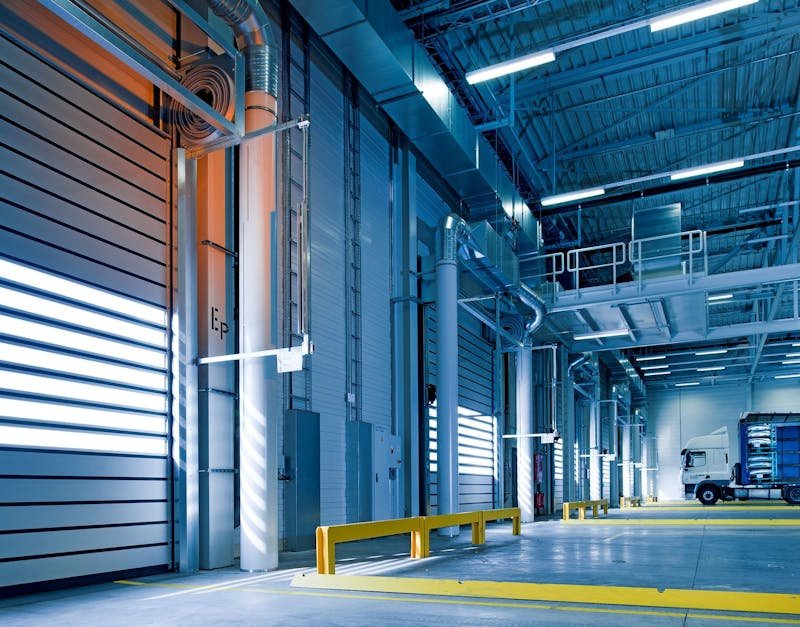 Spacious and modern warehouse interior with parked truck and steel structures.