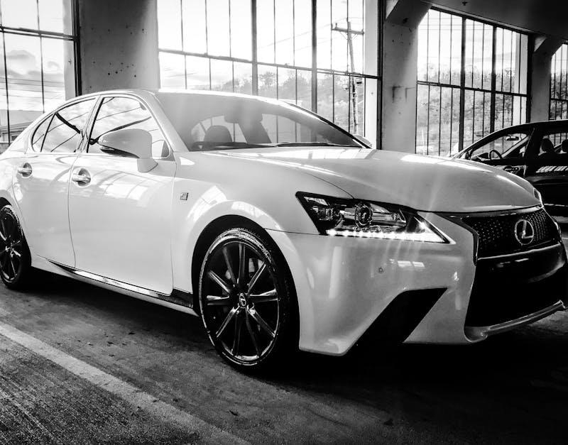 A stylish Lexus sedan showcased in a black and white indoor setting, highlighting its luxury design.
