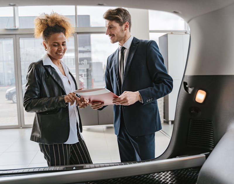 Dealer discussing vehicle options with a client inside a modern car showroom.