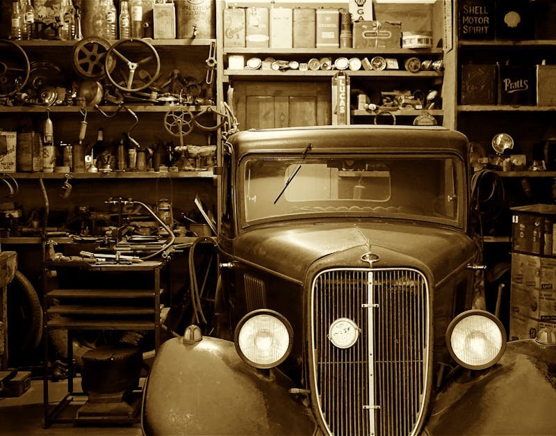A vintage car surrounded by antique tools and parts in a nostalgic workshop.