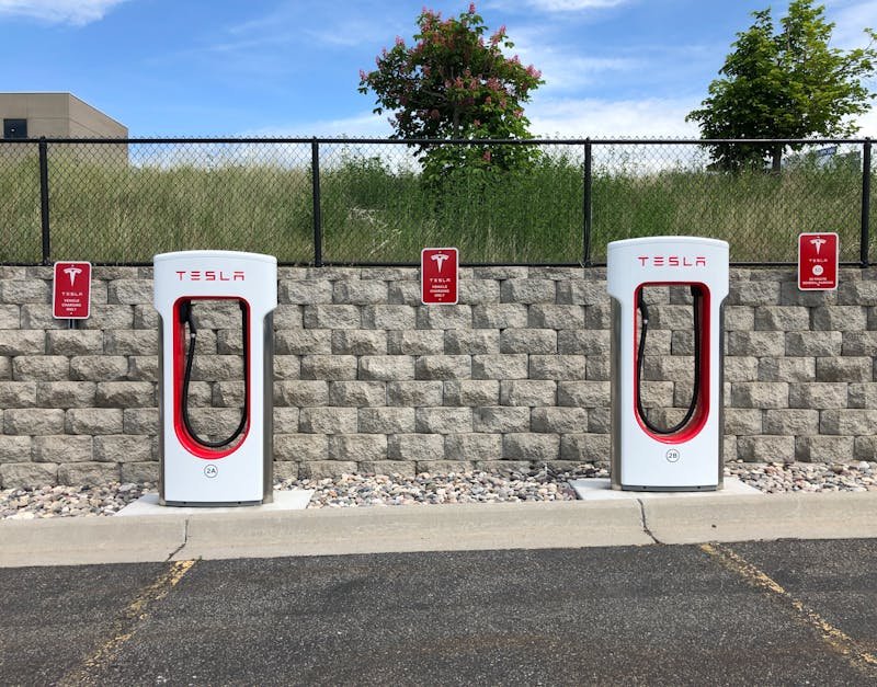 Dual Tesla electric car chargers in Idaho Falls parking lot with clear blue sky.