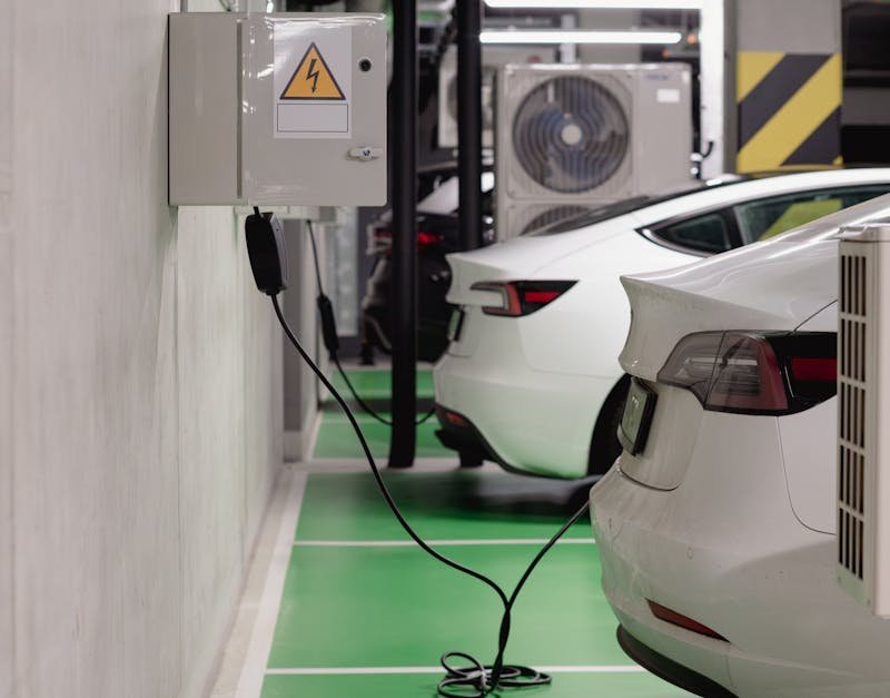 Electric vehicles charging at an indoor station in a modern underground garage.