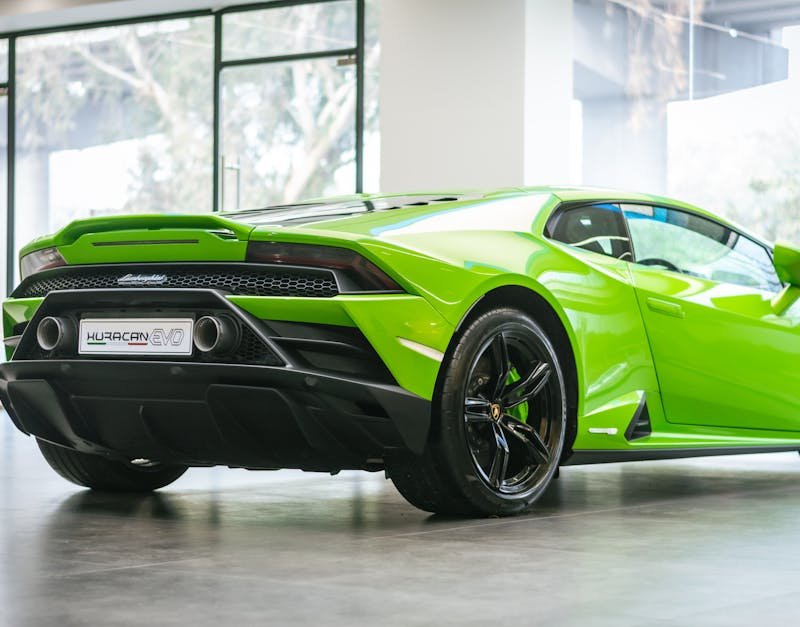 A striking green Lamborghini Huracan EVO parked in a modern showroom, showcasing luxury car design.