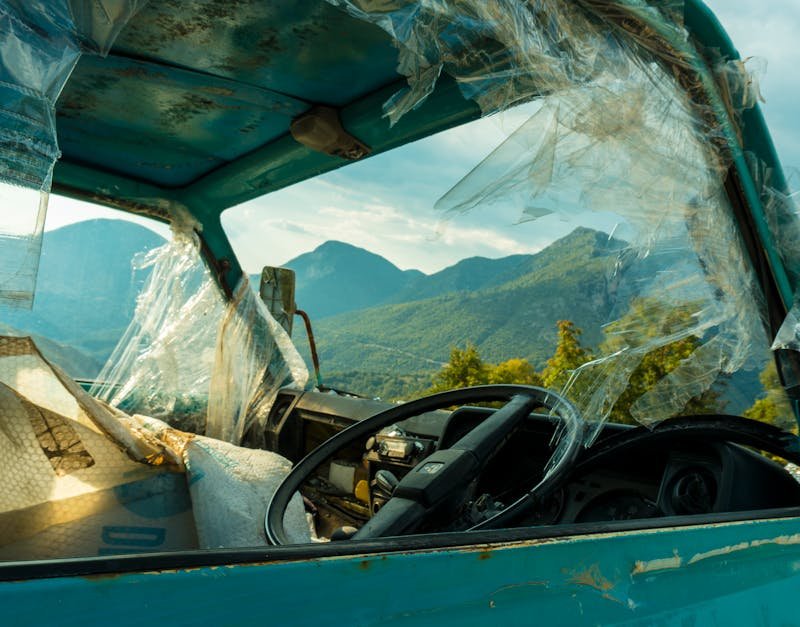 Old rusty truck with broken windows in front of mountain landscape, symbolizing decay.