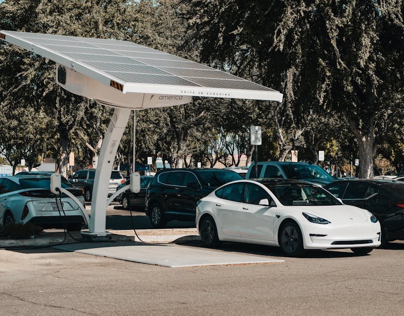 Electric car parked at a solar charging station outdoors, highlighting renewable energy and innovation.