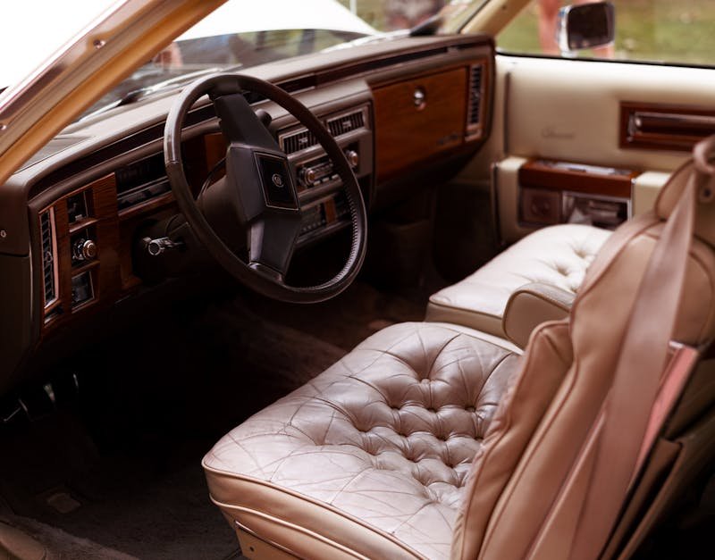 Explore the luxurious interior of a vintage Cadillac with leather seats and wood dashboard.