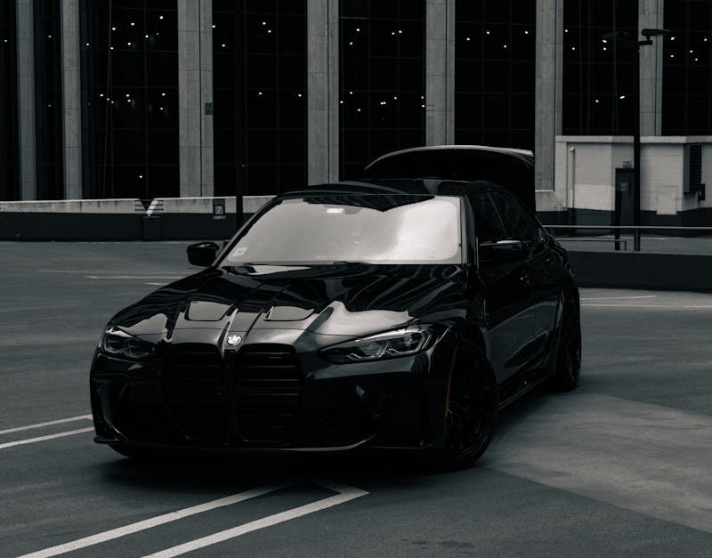 A stylish black BMW M3 on a rooftop in Chicago with skyscrapers in the background.