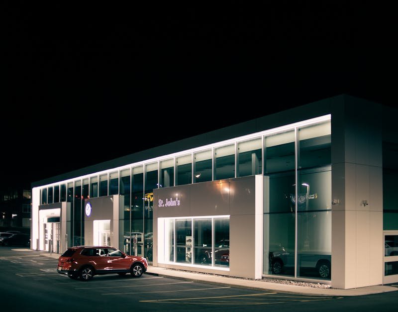 Off road car parked near entrance of shop with luminous lights at dark night