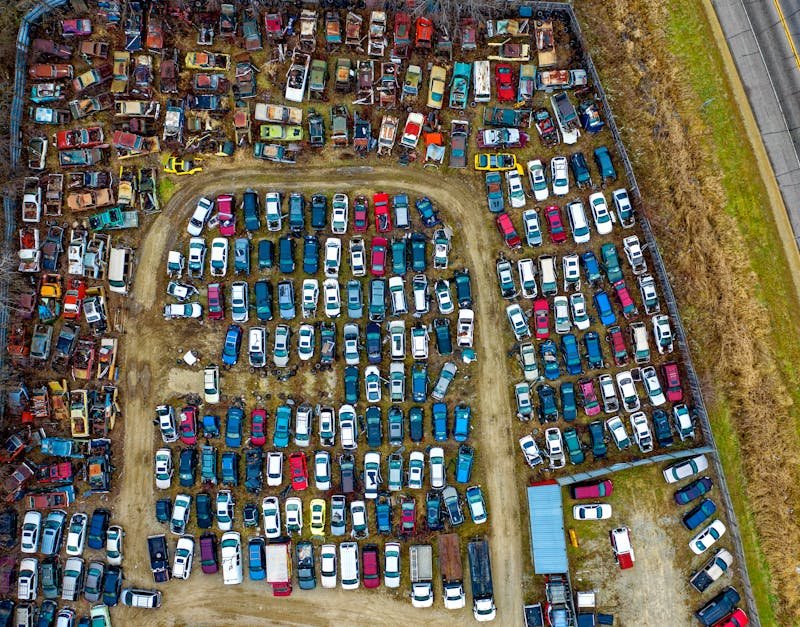 Drone view of a sprawling car junkyard with vintage vehicles in Rochester, MN.