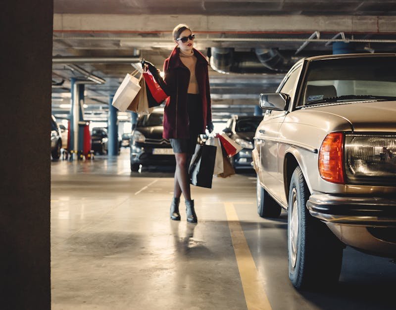 Elegant woman carrying shopping bags in an underground parking garage.
