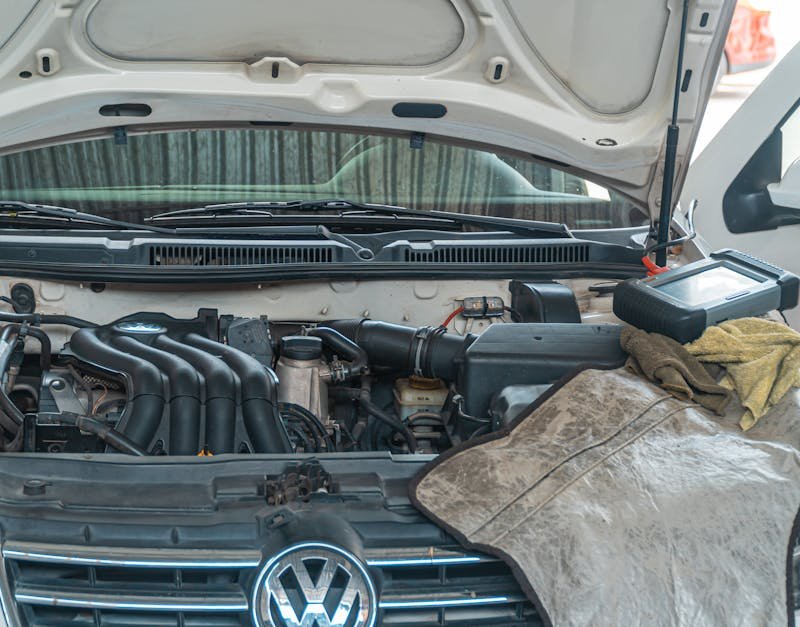 Close-up of a Volkswagen car engine undergoing repair in a garage, tools and diagnostic equipment in use.