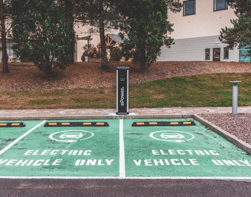 Green electric vehicle parking with charging station in urban environment.