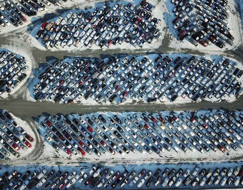 Aerial shot of cars parked in a snow-covered lot, showcasing an organized layout during winter.